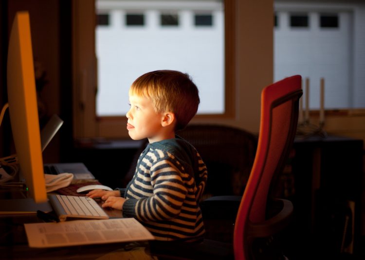 barn der sidder foran en computerskaerm