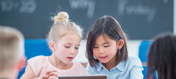 to børn der sidder sammen og deler en tablet