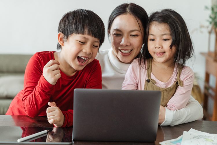 en voksen og to børn sidder sammen foran en computer