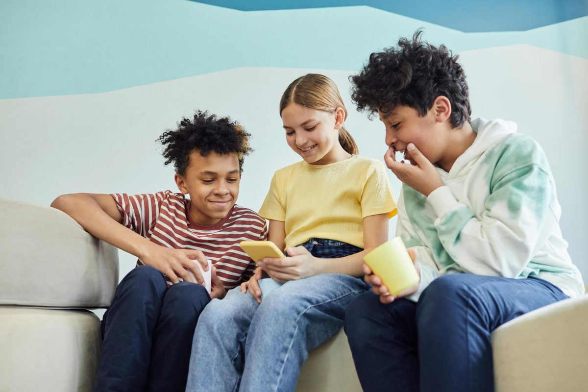 boern der sidder sammen og kigger på en mobiltelefone